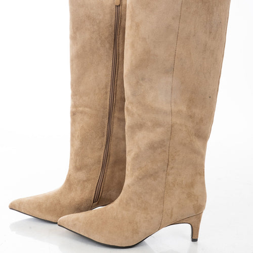 modella indossando Stivali Beige al ginocchio effetto camoscio con tacco medio e punta affusolata colore sabbia