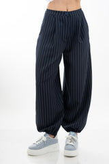 modella indossando Pantalone carrot gessato con pinces e fondo elasticizzato colore Blu Unica