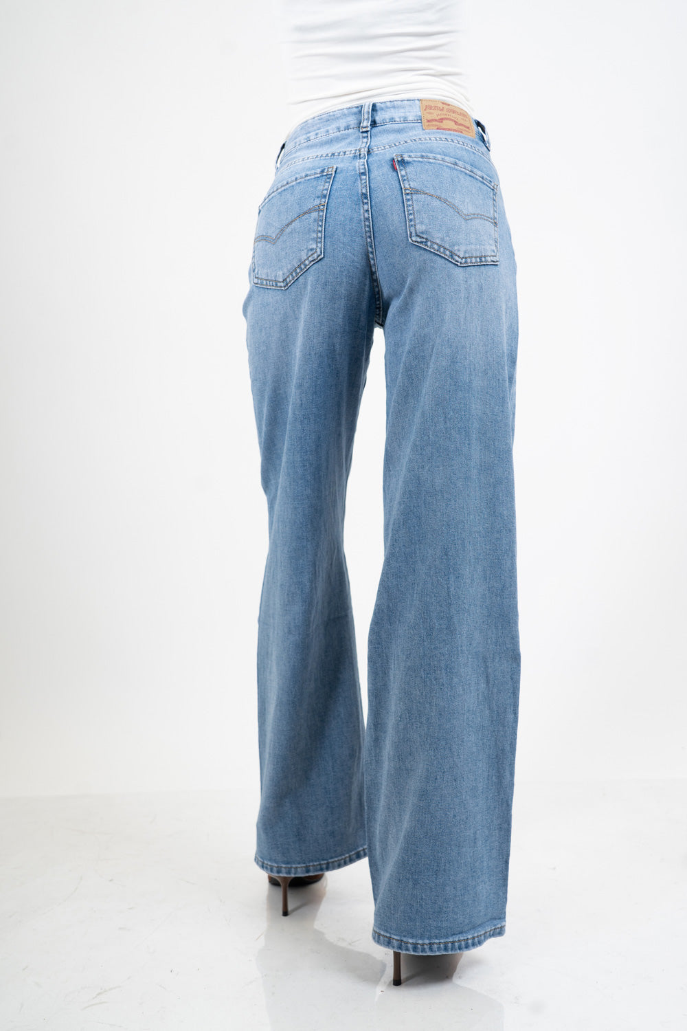 Jeans palazzo a vita bassa in denim lavaggio medio con gamba ampia.
