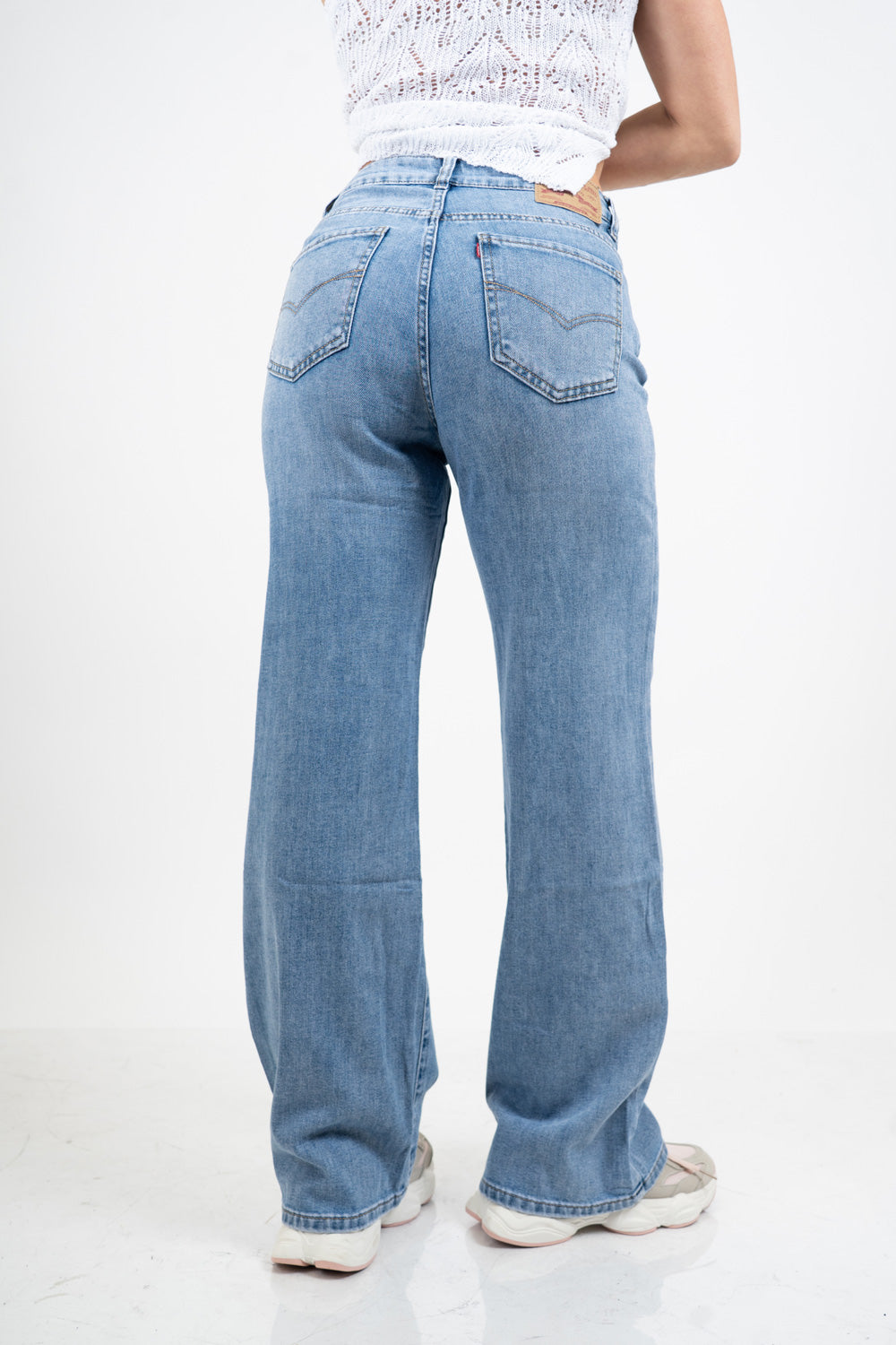 Jeans palazzo a vita bassa in denim lavaggio medio con gamba ampia.
