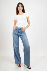 Jeans palazzo a vita bassa in denim lavaggio medio con gamba ampia.