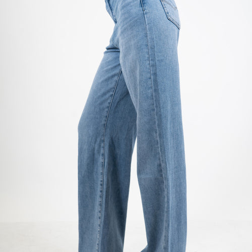 modella indossando Jeans palazzo a vita bassa in denim lavaggio medio con gamba ampia colore Denim Medio