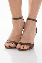 Sandalo marrone con cinturino alla caviglia e tacco alto sottile.