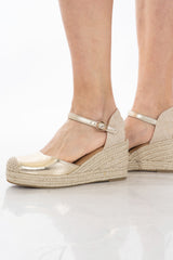 Espadrillas oro con zeppa e cinturino alla caviglia in corda.