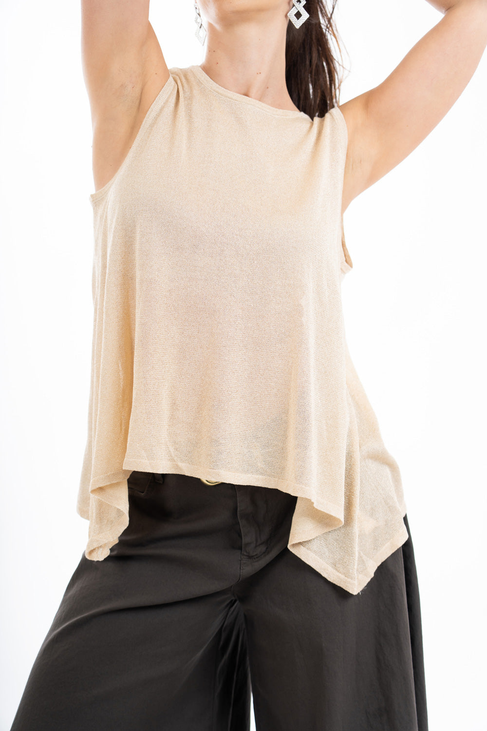 modella indossando Top smanicato in viscosa lurex leggero e semitrasparente, linea svasata e vestibilità morbida. Perfetto per look casual o eleganti. colore Oro Unica