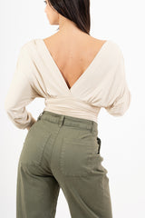 modella indossando Maglia crop drappeggiata con doppio scollo incrociato e spalle strutturate colore