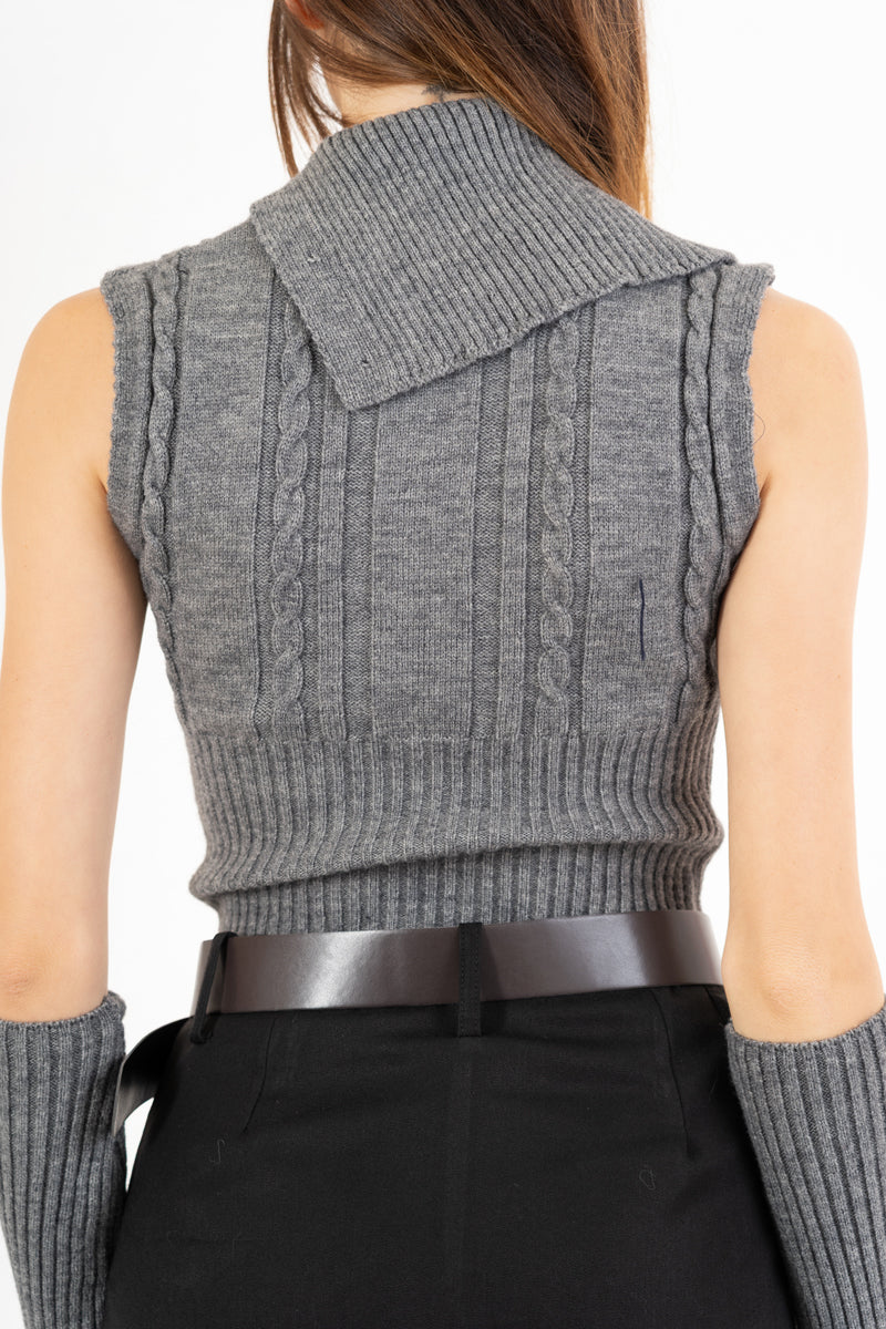 modella indossando Maglia smanicata a trecce con collo alto e bottoni laterali colore