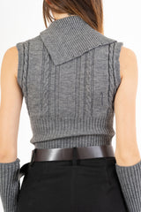 modella indossando Maglia smanicata a trecce con collo alto e bottoni laterali colore