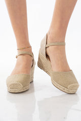 Espadrillas oro chiuse con zeppa in corda e cinturino alla caviglia.