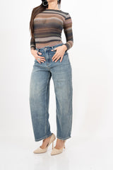 modella indossando Jeans mom fit a vita alta con fondo sfrangiato colore Denim Medio